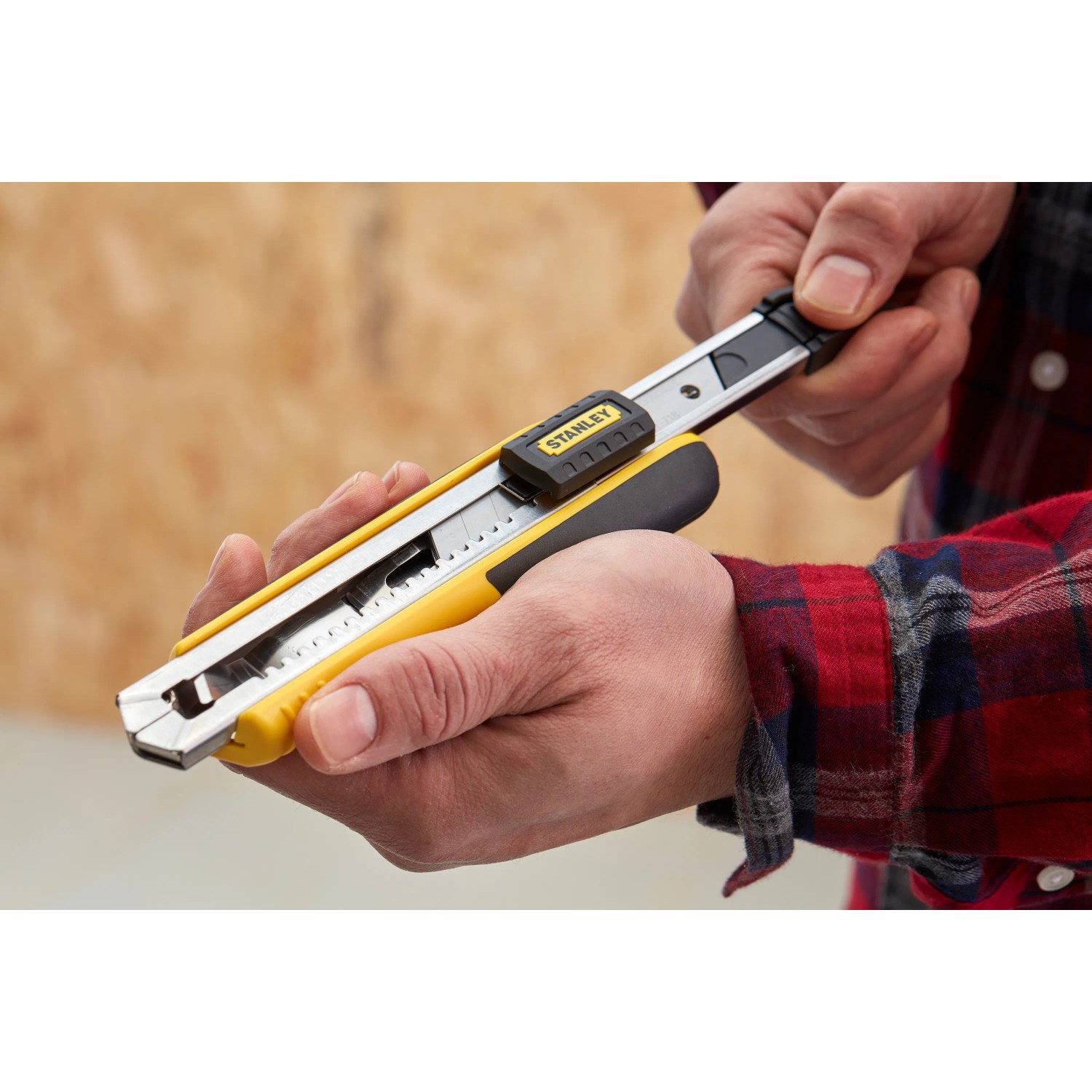 Cutter Stanley FatMax™ 18 mm, nero-giallo, tenuto in mano. Coltello con alimentatore di lame.