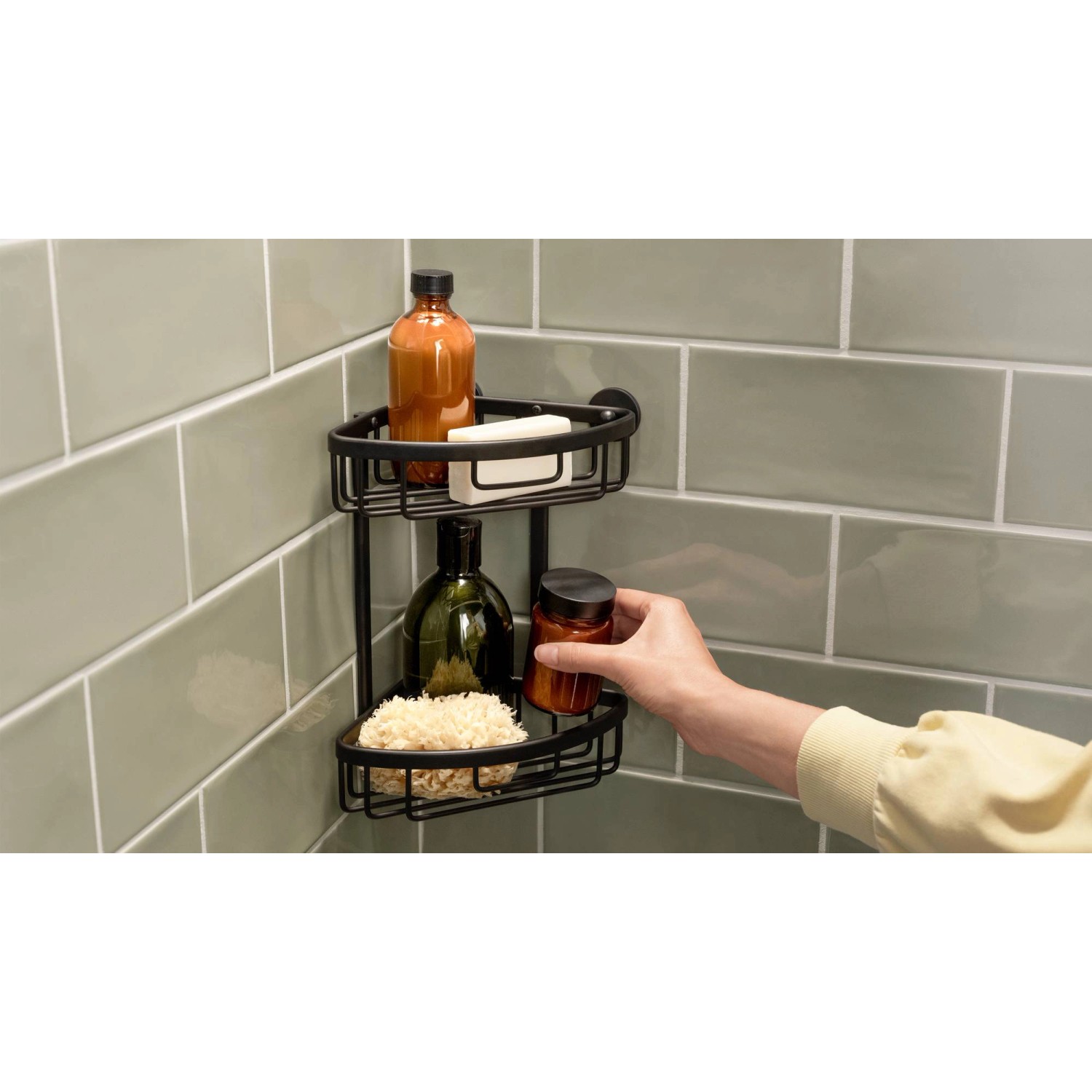 Cestello angolare doccia Tesa Aluxx nero a due piani con accessori doccia su parete verde.