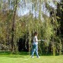 Donna che innaffia il giardino con tubo per irrigazione t.b.t. sotto un albero.