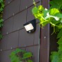 Moderna lampada da parete solare a LED Lutec nera con sensore di movimento montata su una parete di casa.
