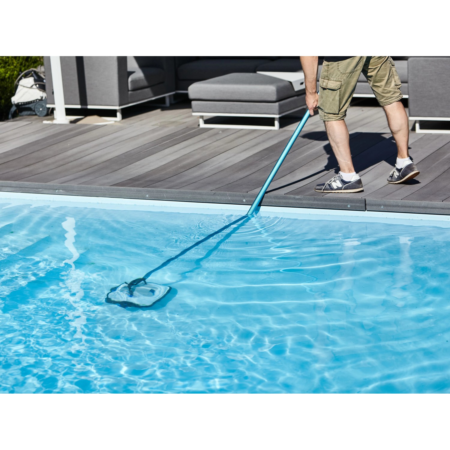 Uomo pulisce la piscina con il robot piscina a batteria Orca 45 CL. Il robot è blu e ha una spazzola.