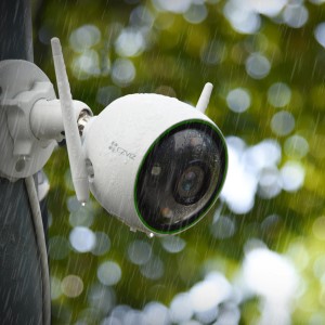 Telecamera di videosorveglianza t.b.t. bianca con due antenne sotto la pioggia.