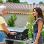 Due donne al barbecue da campeggio nero in giardino. Attrezzatura da campeggio.
