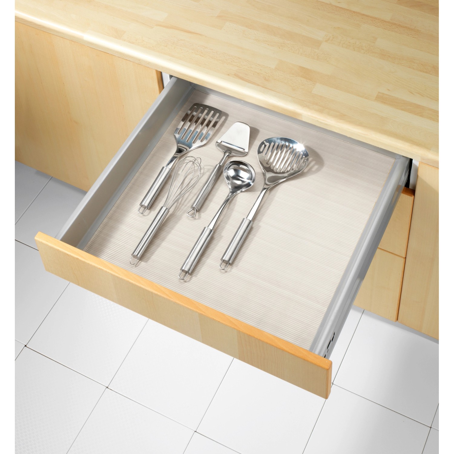 Tappetino antiscivolo trasparente Wenko (150x50 cm) in un cassetto con utensili da cucina.