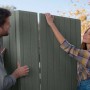 Assemblaggio di una casetta da giardino in plastica grigia. Due persone montano gli elementi.