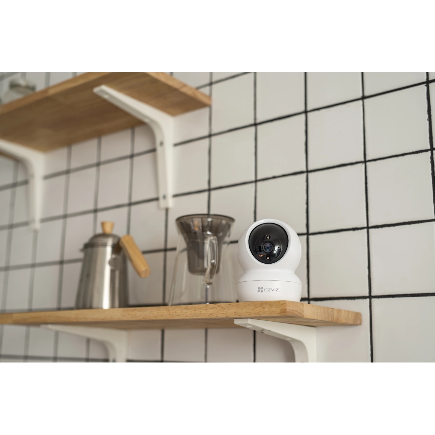 Telecamera di sicurezza bianca su mensola di legno davanti a piastrelle. Videosorveglianza.