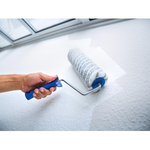 Rullo per pittura LUX 25cm in uso: rullo con manico blu che dipinge una parete bianca.