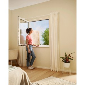Donna alla finestra con zanzariera tesa® Insect Stop Premium antracite. Protezione efficace dagli insetti.