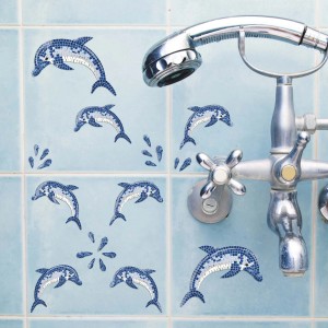 Adesivi murali delfini blu su piastrelle azzurre in bagno.