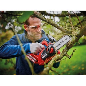 Uomo che sega un ramo con motosega a batteria rossa. Motosega per giardinaggio.