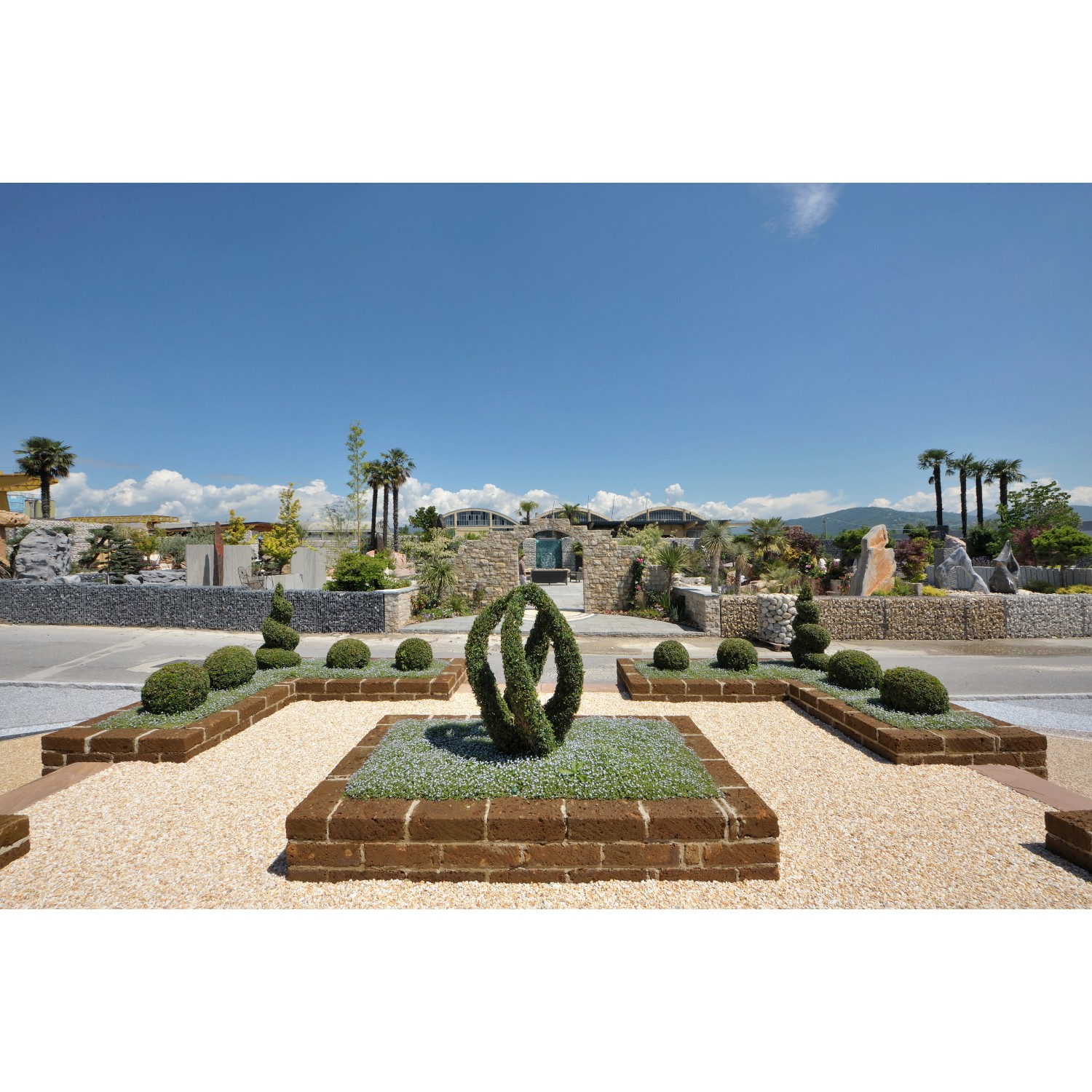 Giardino con bordure t.b.t. e bordi in muratura, arbusti ornamentali e vialetto di ghiaia.