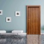 Porta interna in legno marrone in ambiente moderno con sgabelli bianchi e quadri.