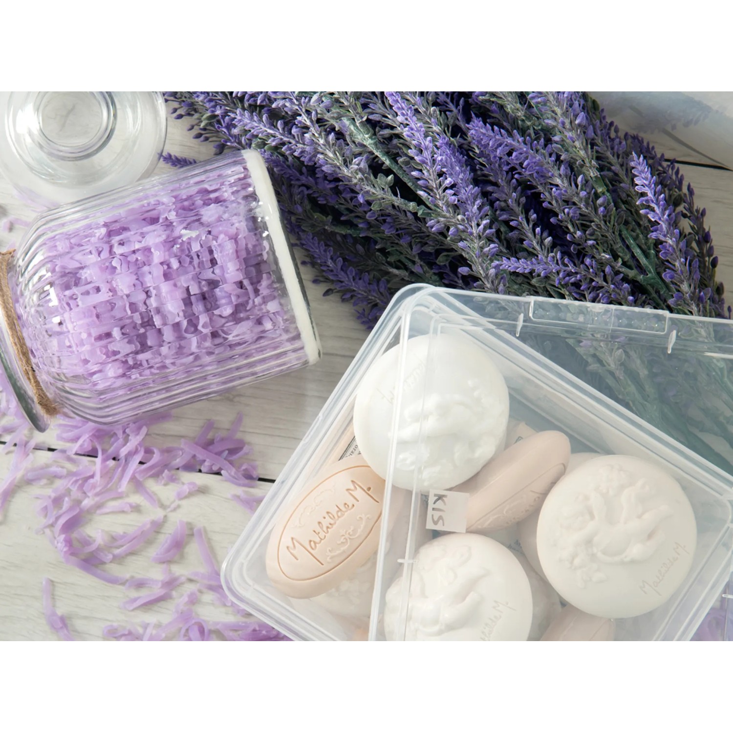 Box contenitore trasparente KIS C XXS con coperchio, riempita con saponi, accanto a lavanda e decorazioni.