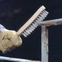 Mano che usa spazzola metallica LUX (4 file, inox) per rimuovere la ruggine dal metallo.