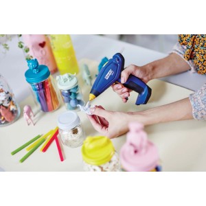 Pistola per colla a caldo blu utilizzata per lavori di bricolage con elementi decorativi.