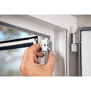 Installazione dell'adattatore per zanzariera Tesa sul telaio in alluminio della porta. Il set è pieghevole e bianco.