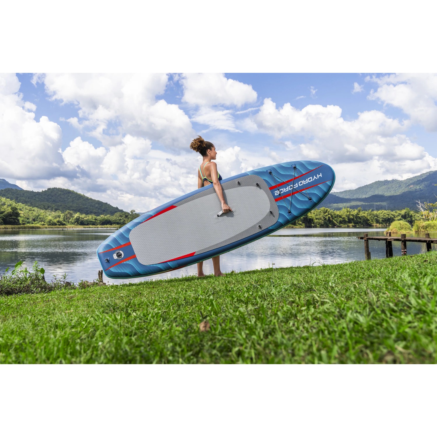 Donna che trasporta la tavola da SUP Allround Bestway Oceana (305 cm) blu al lago.