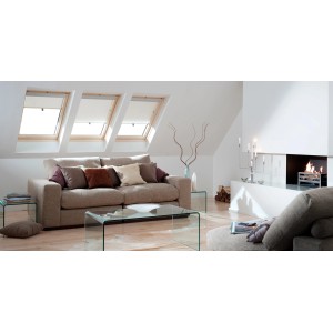 Soggiorno con tre finestre per tetti t.b.t. e divano beige sottostante.