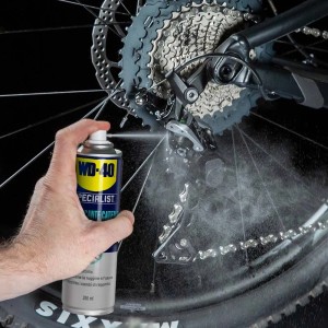 Spray per catena WD-40 in uso su catena e pignone della bicicletta.