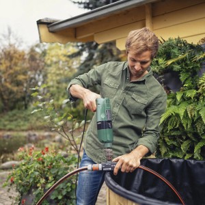 Uomo che utilizza la pompa per trapano Gardena in un laghetto da giardino. Elettropompa con azionamento a trapano.