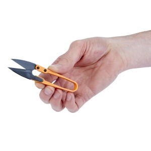 Mano che tiene piccole cesoie per fili arancioni. Strumento di precisione per tagliare i fili.