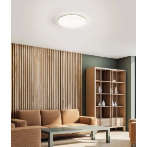 Plafoniera LED t.b.t. bianca e rotonda montata al soffitto in un soggiorno.