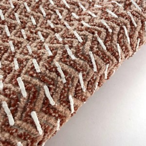 Dettaglio di un tappeto da bagno t.b.t. marrone e beige con accenti bianchi.