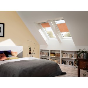 Camera da letto luminosa con due finestre per tetti Velux GGL MK06 2070 bianche con tende arancioni.