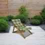 Lettino prendisole in legno con cuscino a quadri verdi in giardino.