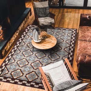 Tappeto a motivi in soggiorno con divano in pelle marrone e tavolo in legno.