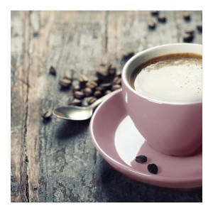 Tazza da caffè rosa con piattino, chicchi di caffè e cucchiaio su superficie in legno.