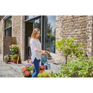 Donna che annaffia le piante con set tubo a spirale Gardena 10 m in giardino.