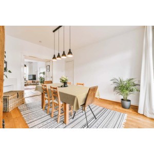 Tavolo da pranzo beige con tovaglia t.b.t. in stanza luminosa con tappeto e piante.