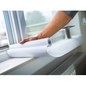 Rotolo di carta protettiva bianca LUX (0,3 m x 10 m) srotolato su un davanzale.