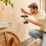 Uomo che fora un muro con trapano avvitatore a percussione a batteria Bosch 18V. Include batteria e custodia.