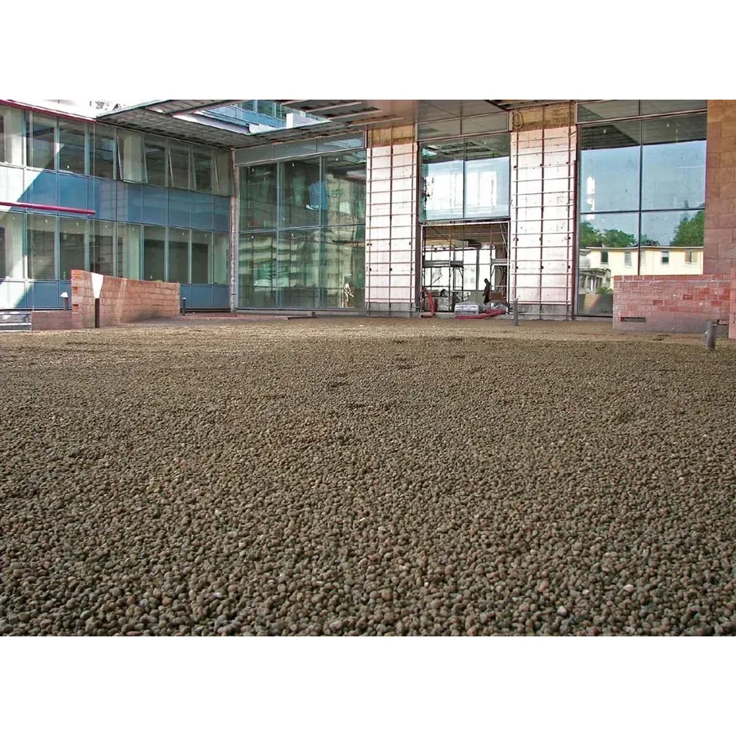 Sabbie t.b.t. marrone come materiale di riempimento su una terrazza sul tetto di fronte a un edificio moderno.