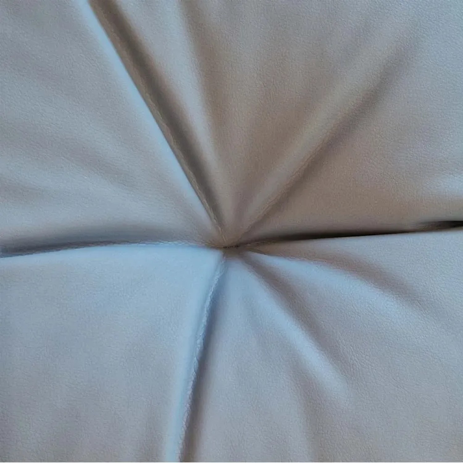 Dettaglio di un cuscino grigio chiaro con motivo trapuntato.