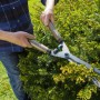 Cesoie per siepi che tagliano una siepe. Strumento per modellare siepi e arbusti.