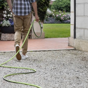 Persona con tubo per irrigazione t.b.t. in giardino.