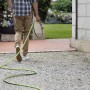 Persona con tubo per irrigazione t.b.t. in giardino.
