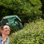 Donna taglia la siepe con il tagliasiepi elettrico Bosch EasyHedgeCut 45. Il dispositivo è verde e nero.