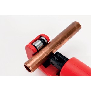 Tagliatubi rosso che taglia un tubo di rame.