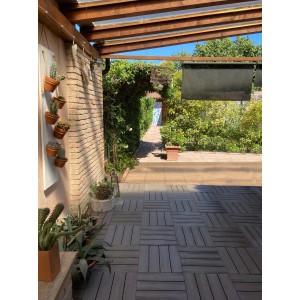 Patio con pavimentazione t.b.t. in piastrelle di legno sotto una pergola con piante.