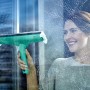 Donna pulisce finestre con Leifheit Window & Frame Cleaner L con manico telescopico.