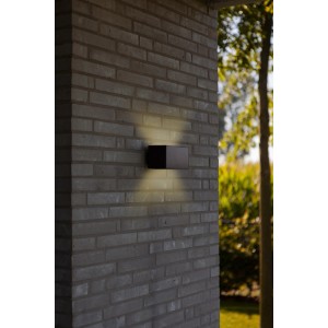 Applique solare nera montata su un muro di mattoni.