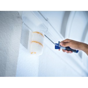 Rullo per pittura LUX 15 cm in uso: mano che dipinge parete bianca con rullo.