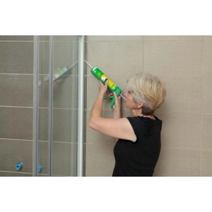 Donna sigilla la doccia con silicone e pistola per cartucce.