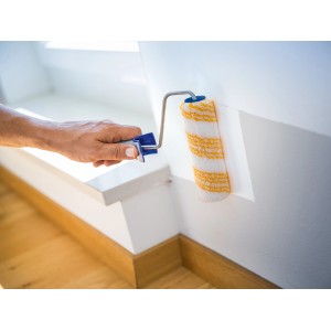 Rullo per pittura LUX da 15 cm mentre dipinge una parete. Rullo con rivestimento in poliammide e motivo a strisce dorate.