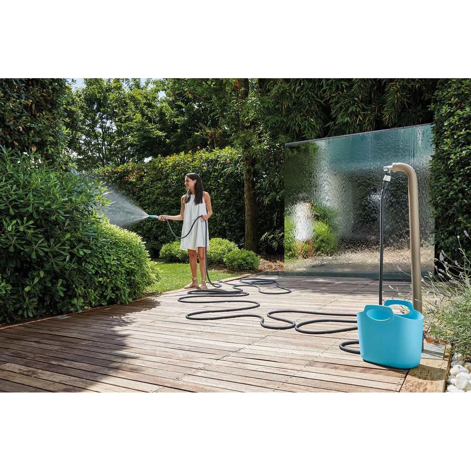 Donna che irriga il giardino con tubo per irrigazione t.b.t. e avvolgitubo.
