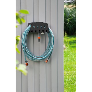Porta tubo da parete Gardena con tubo su muro grigio. Pratico porta tubo da giardino.